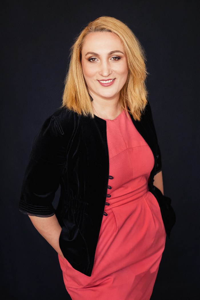 Editorial portrait of Mirela Pascu, coral dress, black jacket, sober background